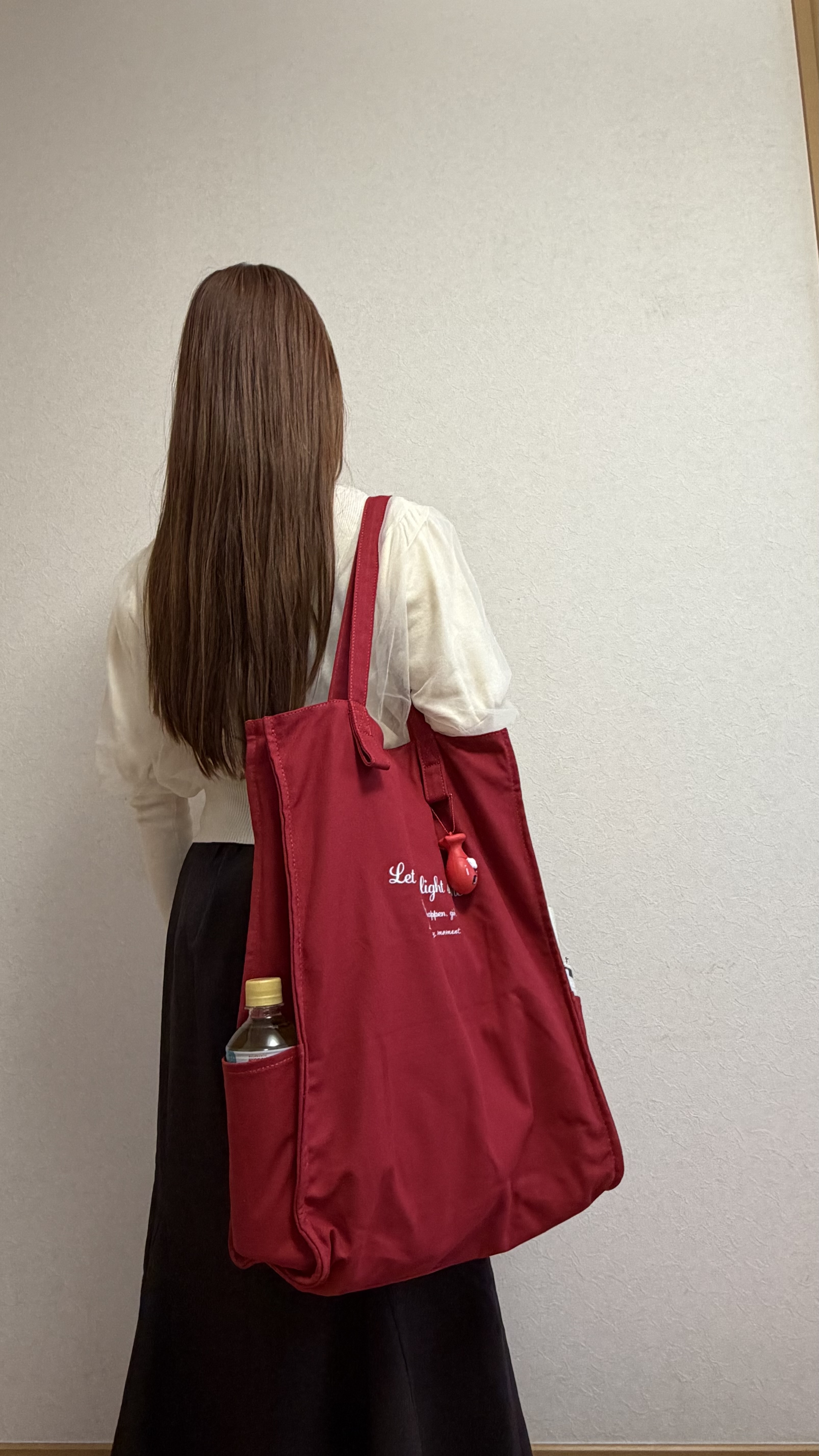 くうが赤いトートバッグを肩に掛けている様子